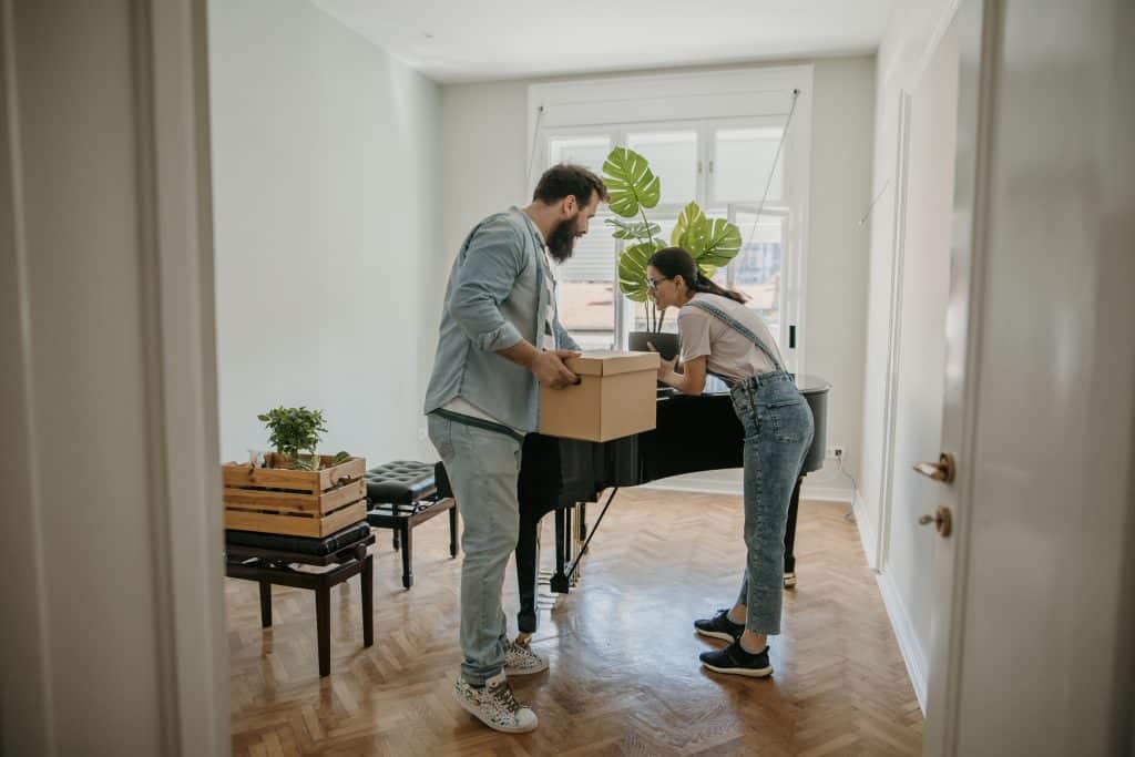 couple in new apartment close to a piano